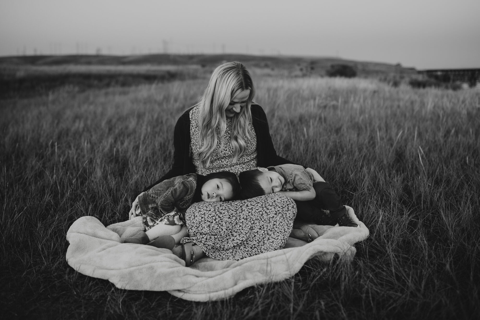 kids snuggling on moms lap in a grassy field