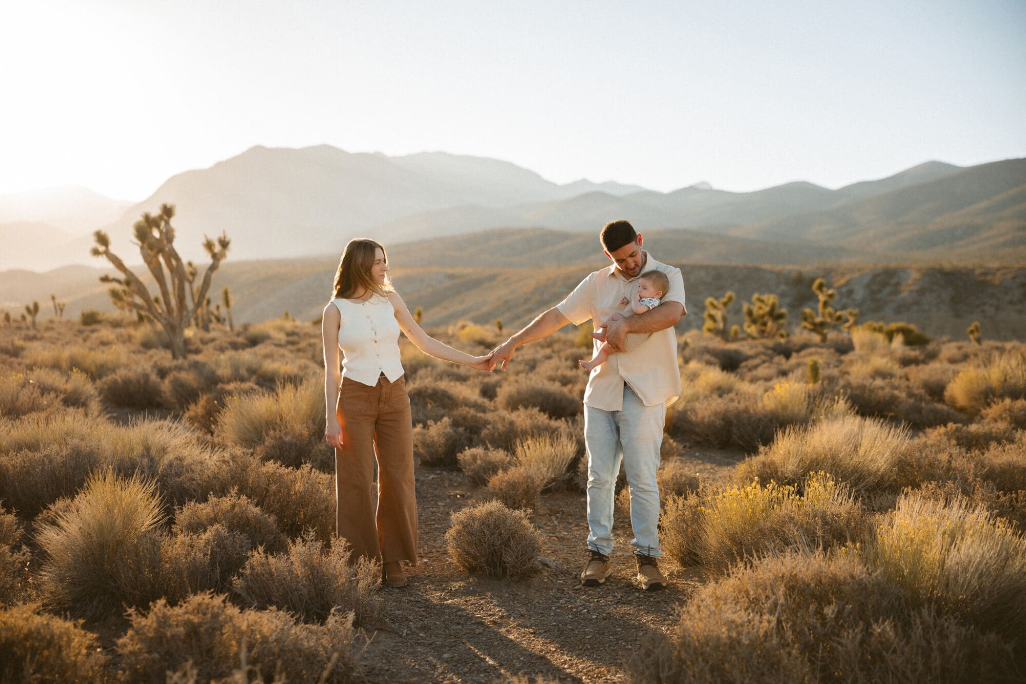 Family standing together outdoors during a relaxed sunset session in Las Vegas, photographed by Myrna Loy Photography. Natural, connection based family photo capturing genuine emotion.