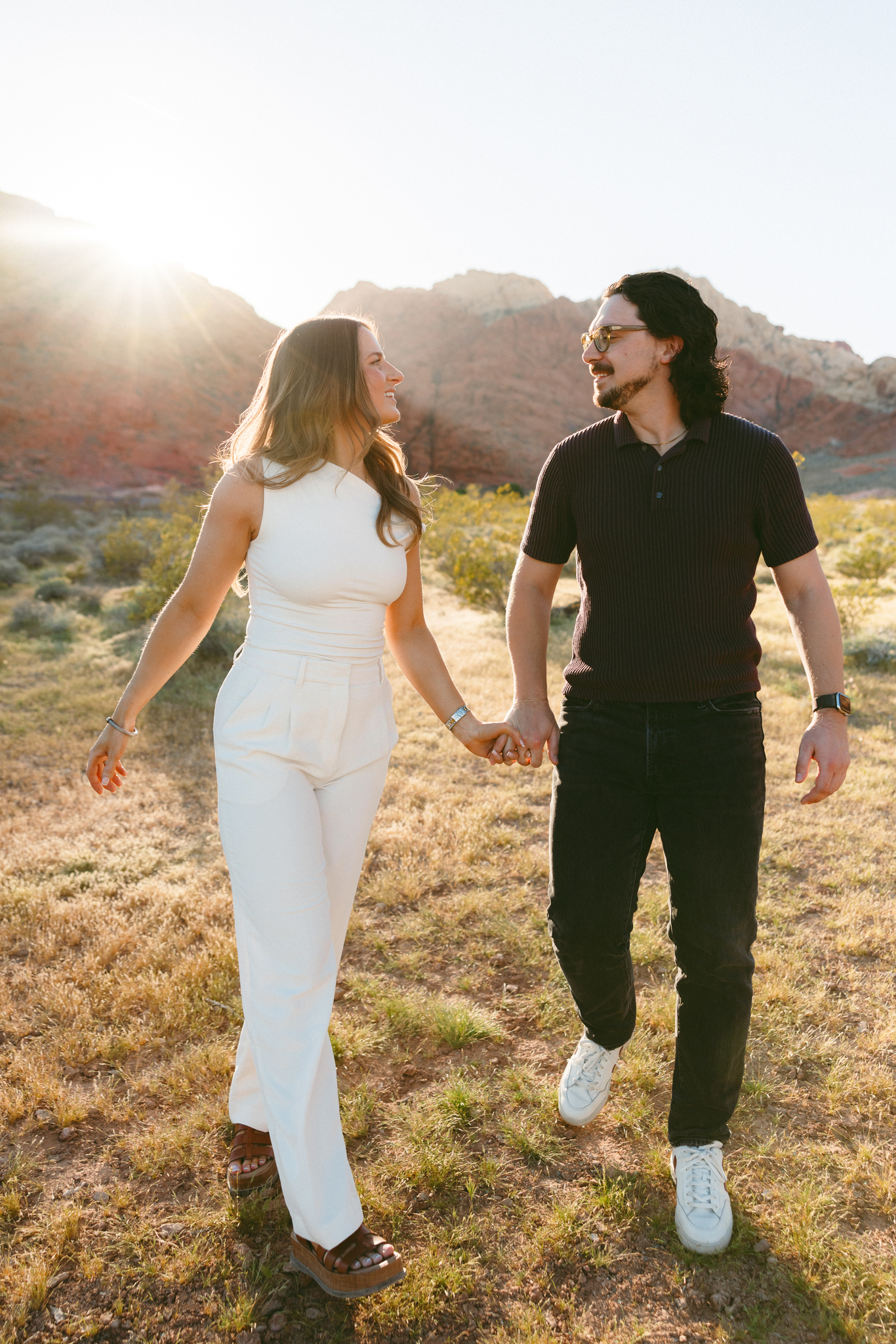 Couple holding hands and laughing while walking through desert landscape in Las Vegas