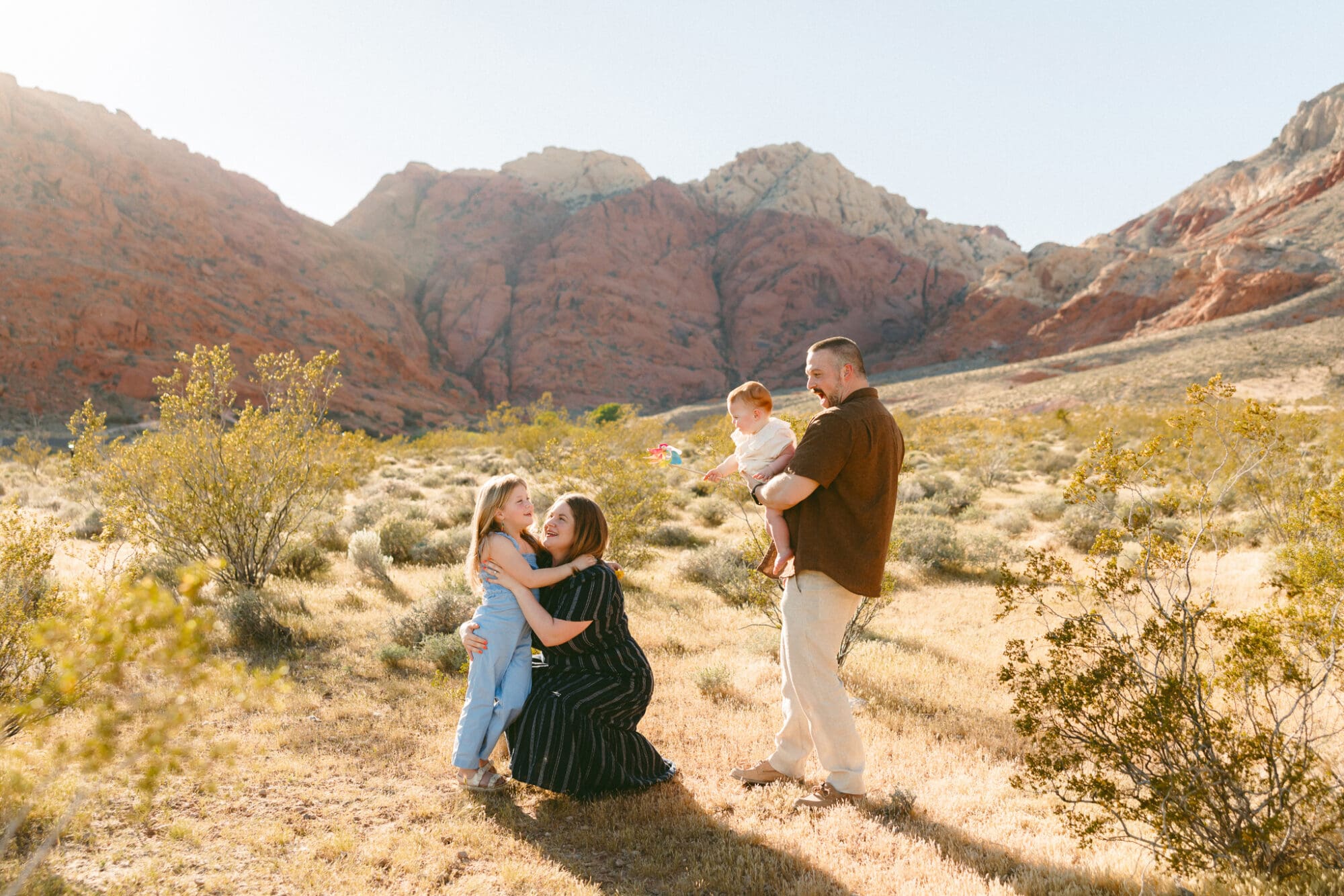 Parents with two young children hugging in open desert landscape near Las Vegas
