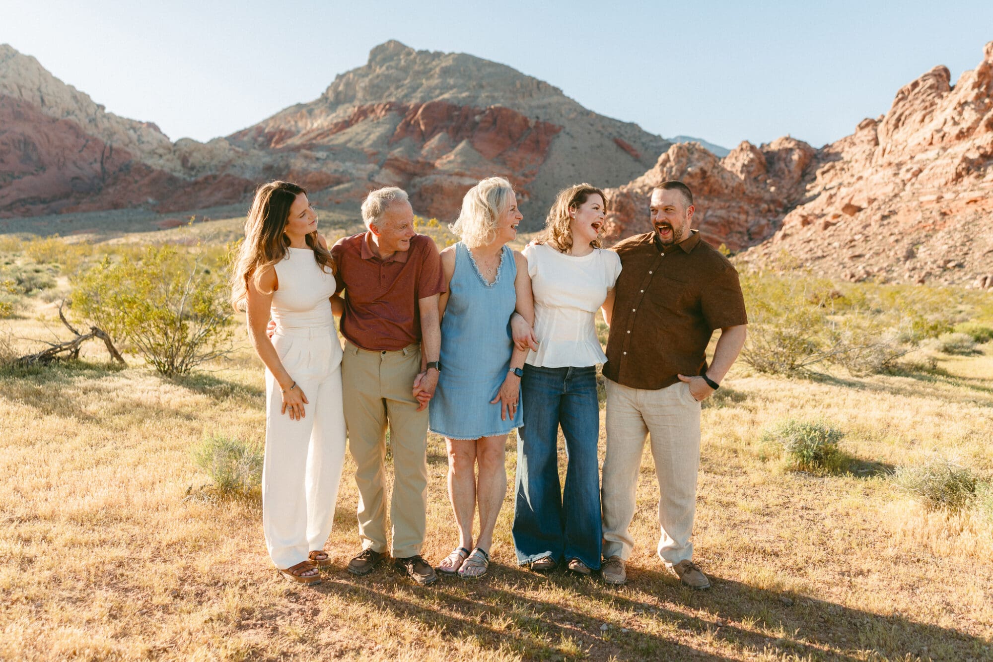 Adult family members laughing together with red rock mountains in the background